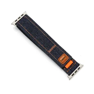 Gros plan détaillé de bracelet de montre en jean tissé avec coutures orange et écusson.