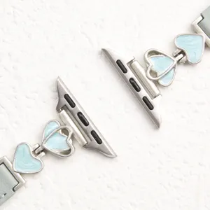 Detailed close-up shot of the heart metal charm and leather watch strap connector detail.
