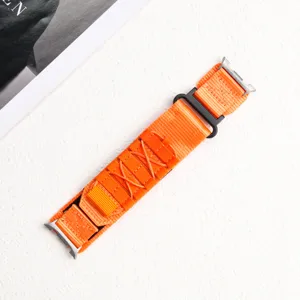 Detailed view of bright orange woven nylon watch strap with metal buckle and loop.