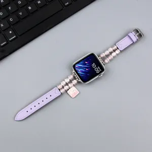 Vue détaillée du bracelet Apple Watch en cuir violet et perles avec charm pendentif en métal.