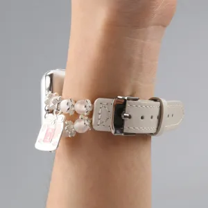 Gros plan sur le bracelet de montre en cuir Apple Watch avec perles et charm porte-bonheur.