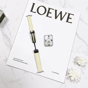 Detail shot of beige leather watch strap with black magnetic folding buckle on a fashion magazine.
