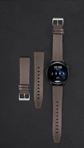 Λεπτομερής όψη καφέ δερμάτινου λουριού smartwatch με αγκράφα από ανοξείδωτο χάλυβα.