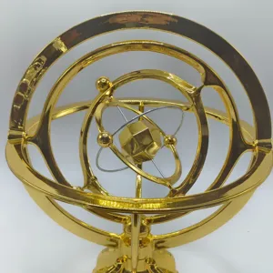 Close-up detail of the gold metallic armillary sphere desk ornament with rotating orbital rings.