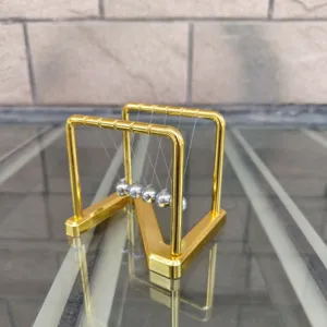 Detailed view of metal Newton cradle balance balls, gold frame desk toy for home office decor.