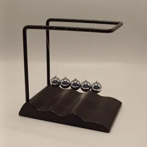 Close-up detail of the metal Newton cradle with unique wave base and polished chrome balls.