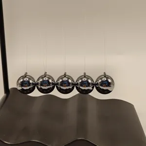 Close-up detail of the Newton's cradle featuring shiny metal spheres and wave base.