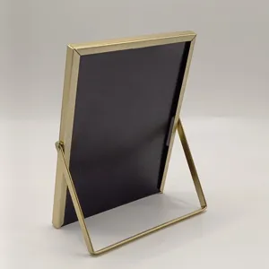 Gold metal picture frame detail, rectangular tabletop photo holder with sturdy folding stand.