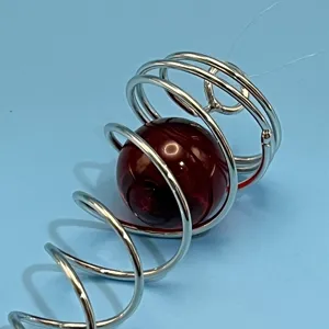 Edelstahl Spirale Windspiel Detailaufnahme mit glänzender silberner Drahtform und roter Glaskugel.