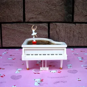 Close-up detail of white piano music box with rotating ballerina figurine for desk decor.