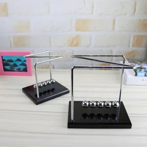 Z-shaped Newton cradle balance balls detail shot, showing metal frame and wood base setup.