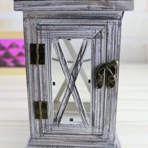 Close-up detail of vintage distressed wooden candle lantern with rustic metal hinges and latch.