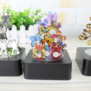 Close up of magnetic balance toy with colorful butterfly and human figures on black base.