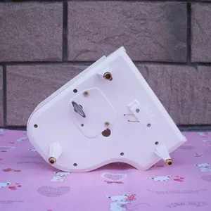 Detailed bottom view of white piano music box showing mechanical wind-up key and plastic legs.