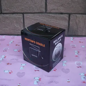 Detailed view of Newton's cradle balance balls packaging box, physics desk toy display.