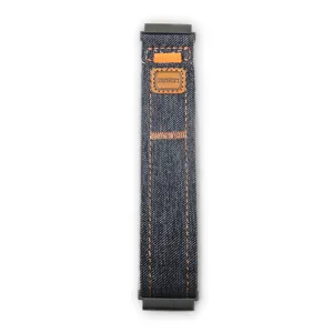 Primo piano dettagliato del cinturino per orologio in tela di jeans blu con chiusura in velcro.