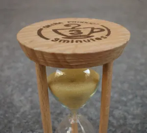 Close-up detail of the wooden top cap and glass hourglass structure with gold sand.