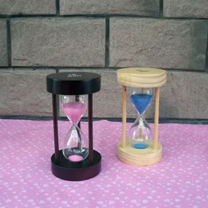 Nahaufnahme der hölzernen 15-Minuten-Sanduhr mit farbigem Sand vor rustikalem Hintergrund.