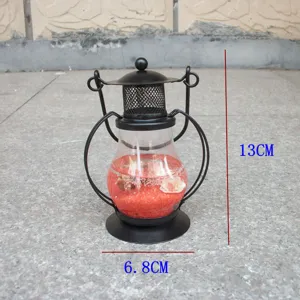 Aladdin lamp shaped gel candle holder with black metal frame and red decorative sand inside.