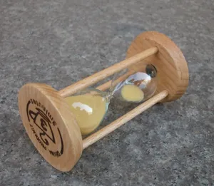 Detail shot of a wooden 3-minute sandglass timer with yellow sand for desktop decor.