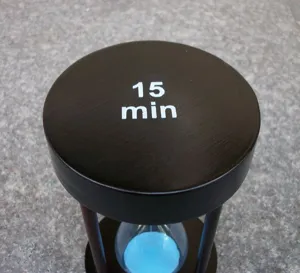 Nahaufnahme Detailansicht einer schwarzen Holzsanduhr mit blauem Sand für 15 Minuten Zeit.