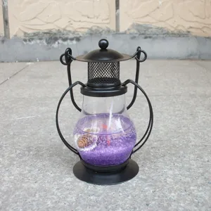 Detail view of the black metal jelly candle holder with purple sand and shells inside.