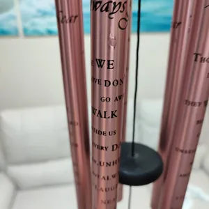 Detail view of memorial wind chime metal tubes with English engraved quotes for garden decor.
