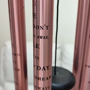 Metal memorial wind chime tube detail showing engraved sentimental English text for outdoor garden decoration.