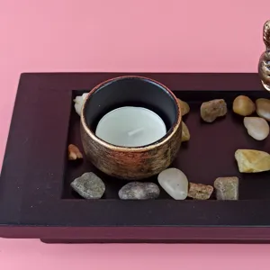 Detail shot of Southeast Asian style Ganesha incense tray with candle and decorative stones.