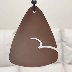 Detailed closeup of the brown decorative pendant with unique cutout design and black hanging cord.