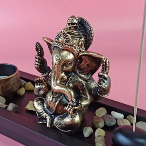Detailed view of Ganesha statue with incense tray, stones, and candle holder for home decor.