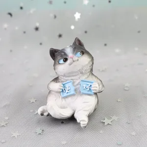 Close-up detail of cute resin cat figurine holding sign, perfect for car or home decor.