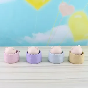 Close-up of cute resin little pig ornaments in colorful pots, detail view for decor.