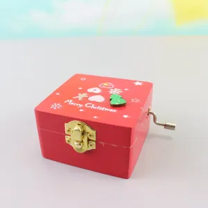 Wooden hand crank music box detail view featuring festive red finish and mechanical handle.