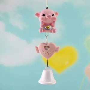 Cute pink pig hanging wind chime detail, resin ornament with heart pendant and bell for home decor.