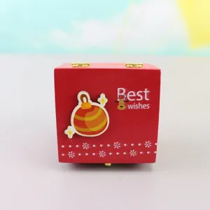 Wooden Christmas hand-cranked music box, detail view of red gift box with cute holiday decor.