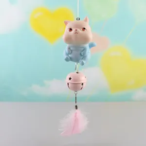 Closeup detail of cute cat figurine hanging ornament with pink bell and soft feather decoration.