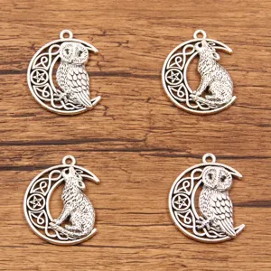 Close-up detail of antique silver alloy crescent moon owl and wolf charms for DIY jewelry making.
