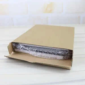 Detail view of the geometric glass and metal photo frame in secure mailer packaging.