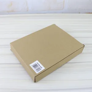 Detail shot of brown cardboard packaging box with product barcode and SKU label on wooden table.