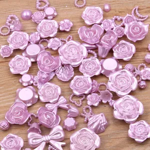 Close-up detail of mixed pink resin rose flower and bow flatback cabochons for DIY crafts.
