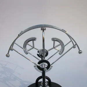 Close-up detail of the metal kinetic sculpture ornament, showing silver swinging balance balls.