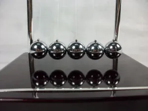 Primer plano detalle de las brillantes bolas de metal pulido y pilares para péndulo.