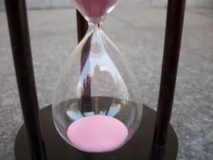 Detailaufnahme einer kreativen 15-Minuten Sanduhr aus Holz mit rosa Sand als Tischdeko.