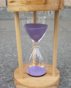 Detailansicht der hölzernen Sanduhr mit lilafarbenem Sand zur Veranschaulichung der Textur.