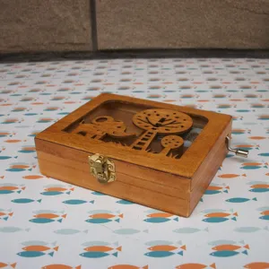 Wooden music box detail featuring cute elephant and tree carved lid design with metal crank.