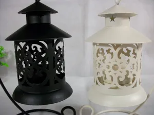 Gros plan detail de bougeoirs en fer creux noir et blanc avec des motifs floraux.