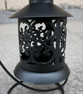 Gros plan détaillé d'un bougeoir lanterne en métal noir creux au design rétro et élégant.