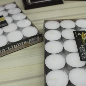 Detailed shot of white round tea light candles in aluminum cups, smokeless design for weddings.