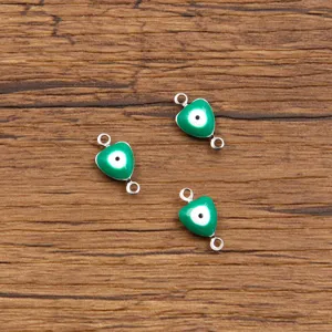Close-up of green heart evil eye stainless steel jewelry connectors, detail view of charms.